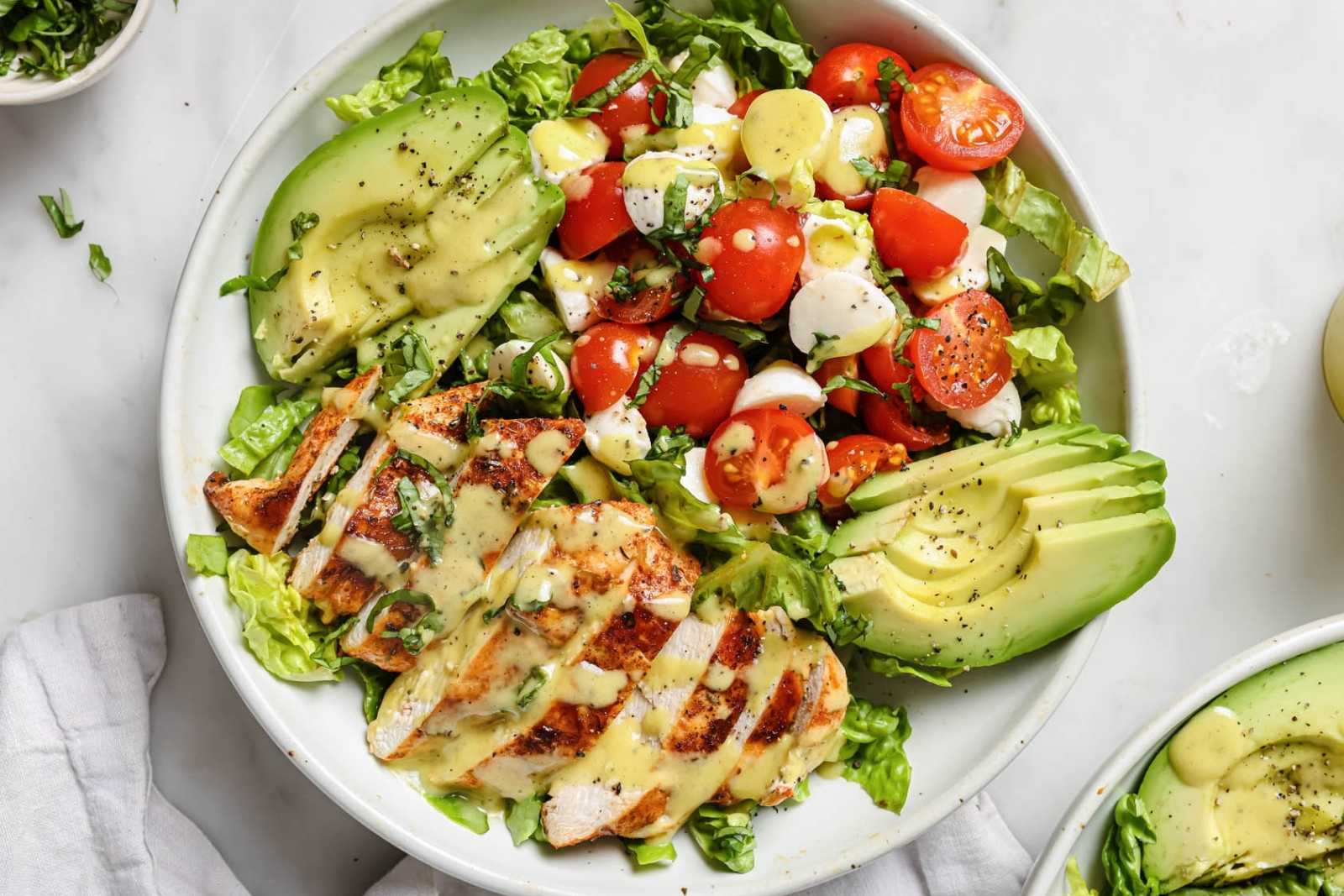 a big plate with blackened chicken salad with avocado, tomato, lettuce, and mozzarella balls