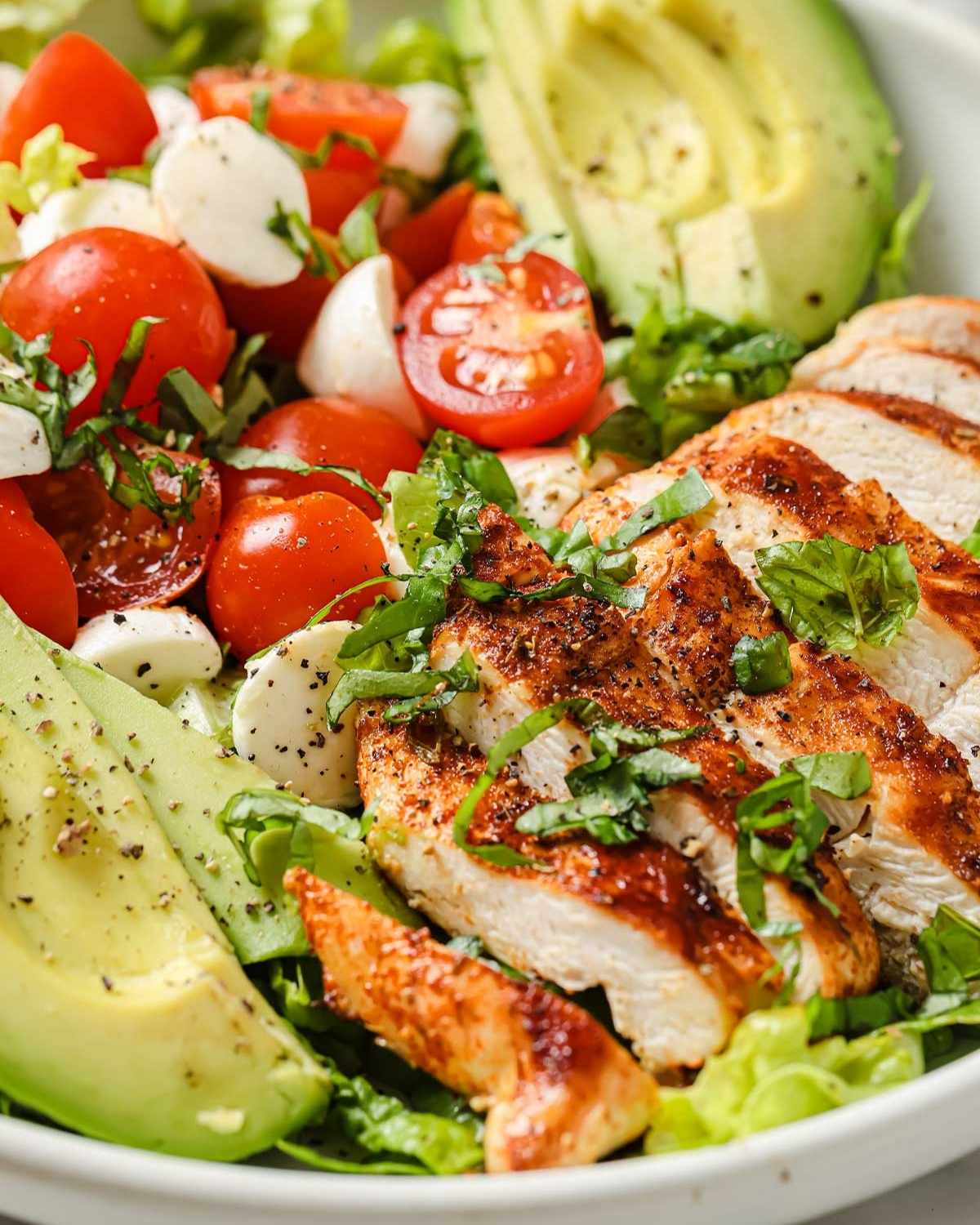 close up of blackened chicken salad with avocado, tomato, and mozzarella balls