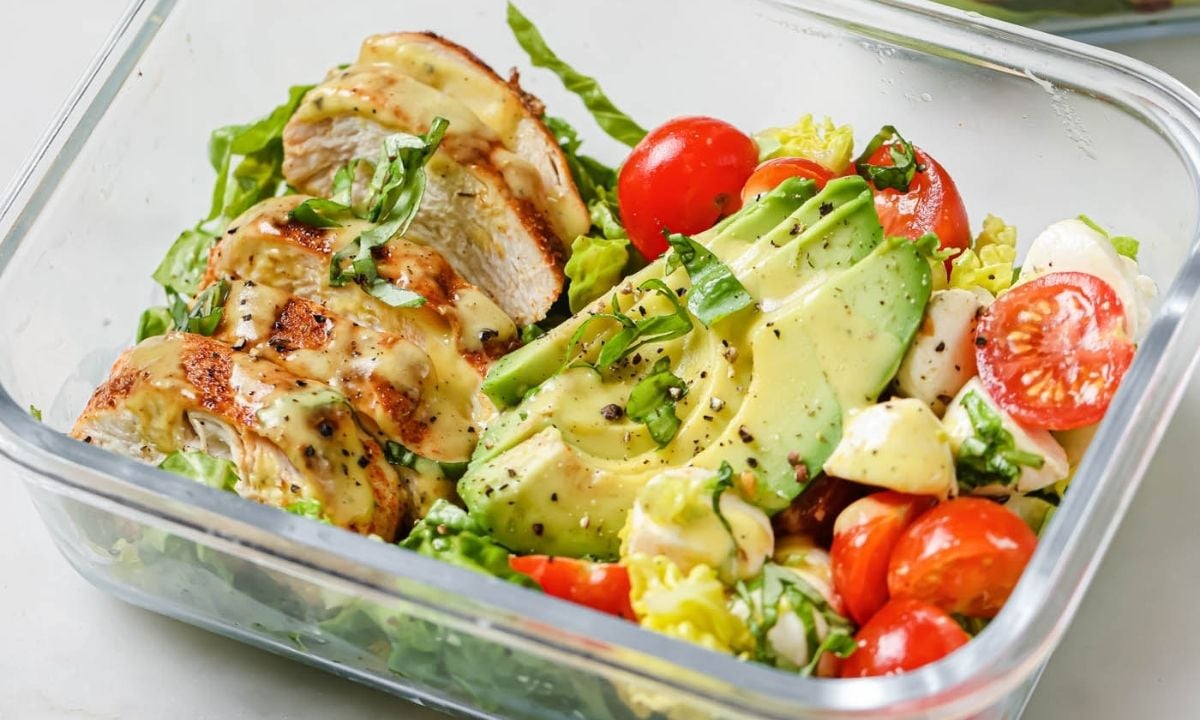 glass lunchbox with blackened chicken salad with avocado, tomato, lettuce, and mozzarella balls