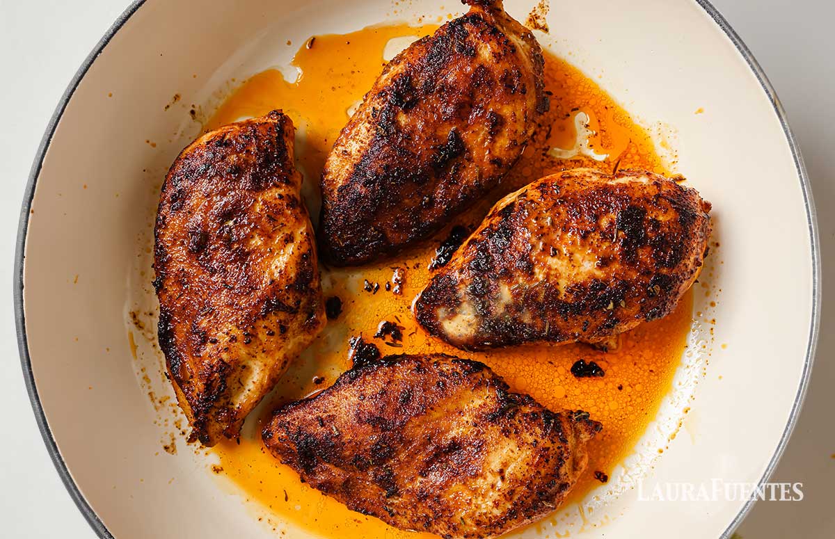 four blackened chicken breasts on a white pan