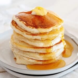Pancakes without eggs on a plate topped with syrup and butter