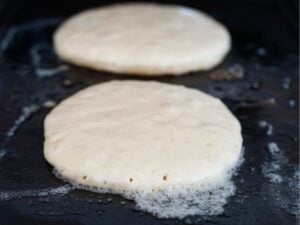 cooking pancakes on a griddle, first side