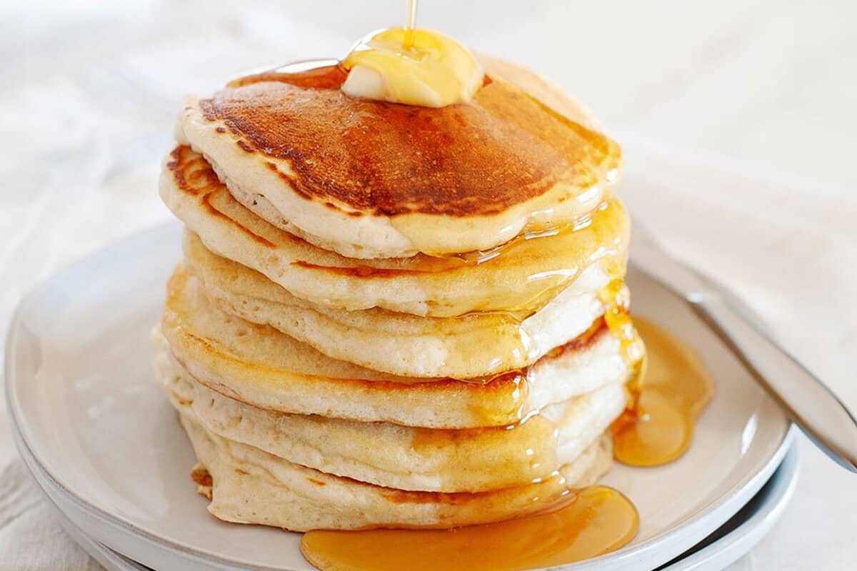 Pancakes without eggs on a plate topped with syrup and butter