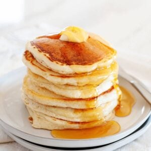 stack of pancakes made without eggs on a plate topped with syrup and a pat of butter.