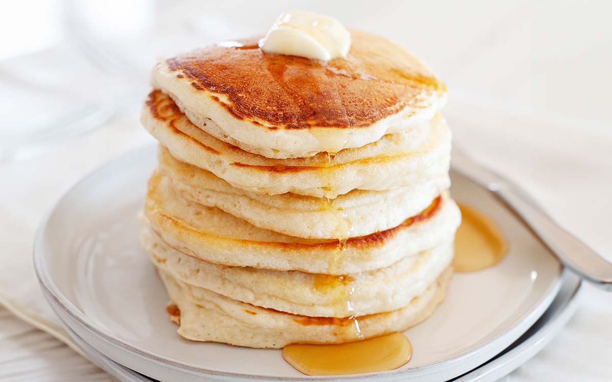fluffy stack of pancakes made without eggs on a plate with a light drizzle of syrup