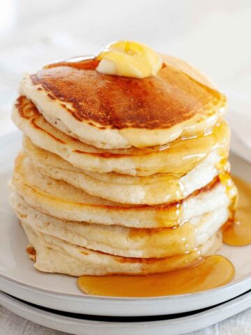 stack of pancakes made without eggs on a plate topped with syrup and a pat of butter.