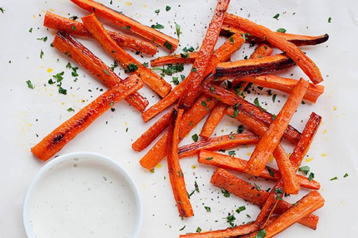 carrot fries on a white plate with a small dish of ranch dressing