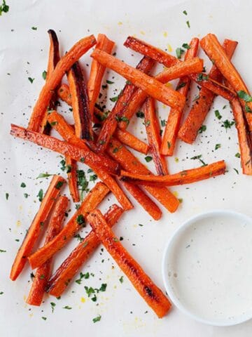carrot fries on a white plate with a small dish of ranch dressing