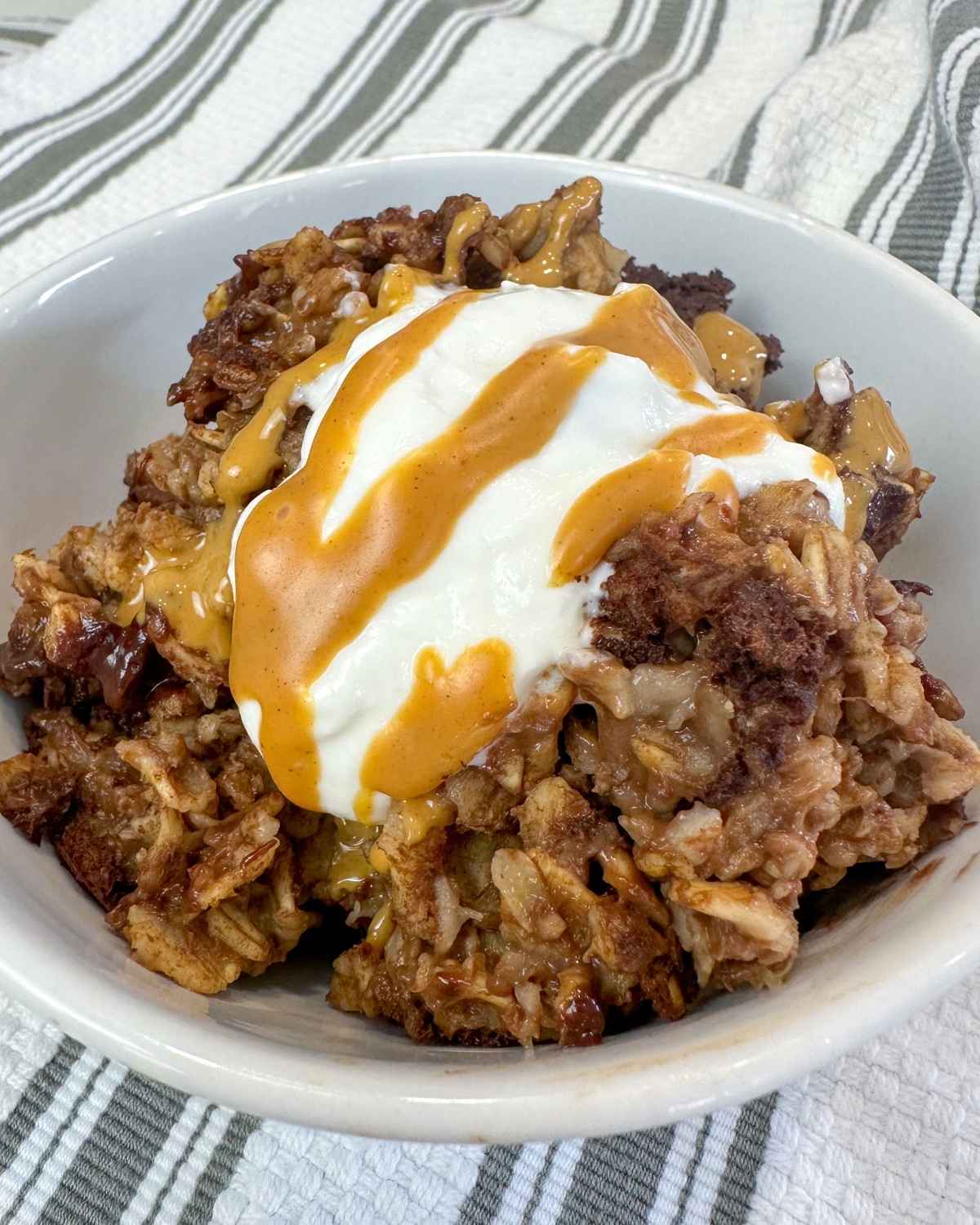 a bowl of chocolate baked oatmeal topped with Greek yogurt and peanut butter