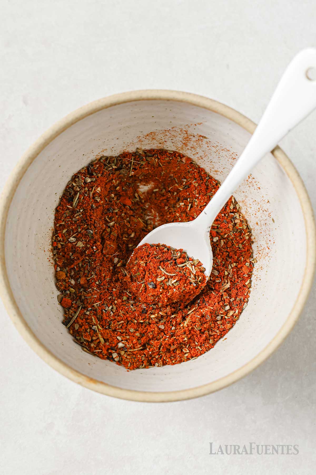 small bowl of homemade cajun seasoning with a small white spoon to mix