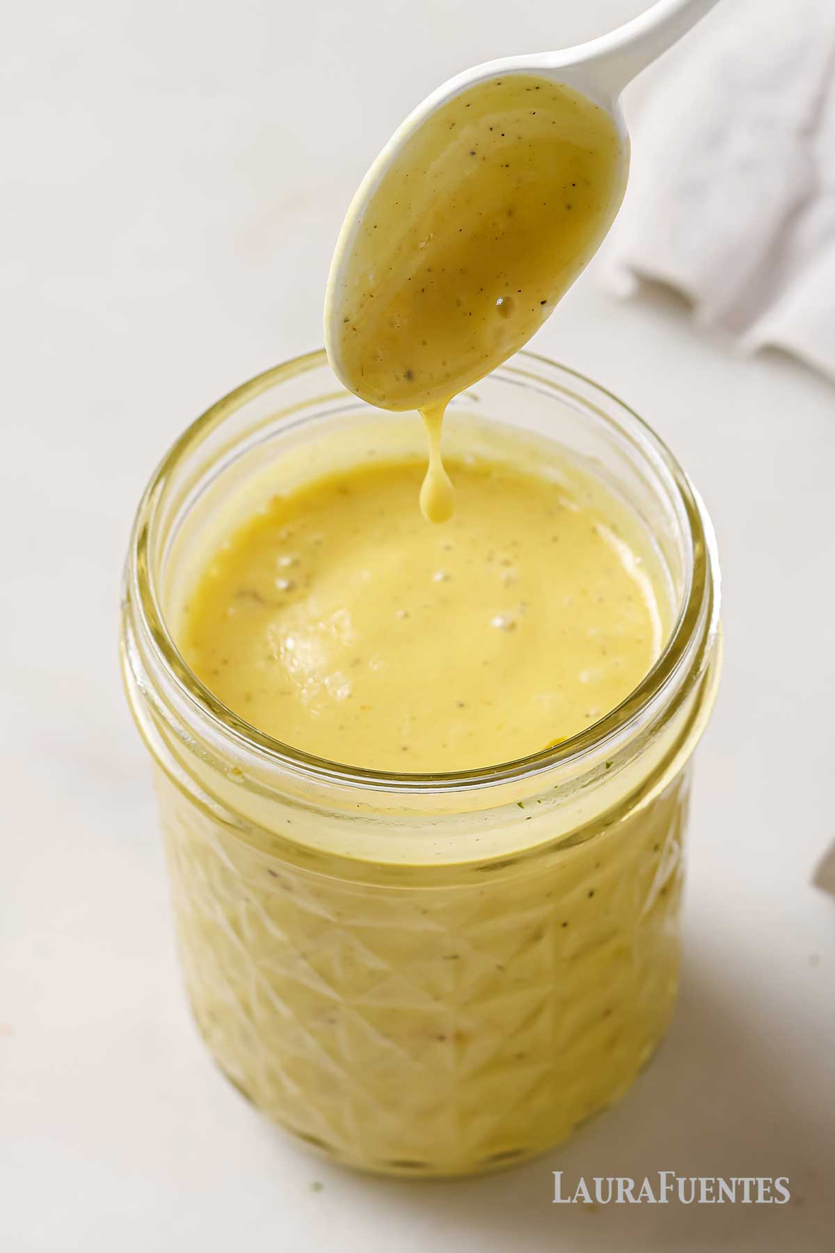 white wine vinaigrette in a glass jar with a spoon