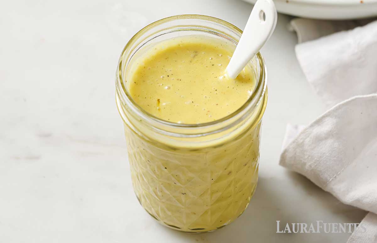 white wine vinaigrette in a glass jar with a spoon