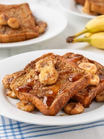 banana french toast in a white dish with banana slices on top