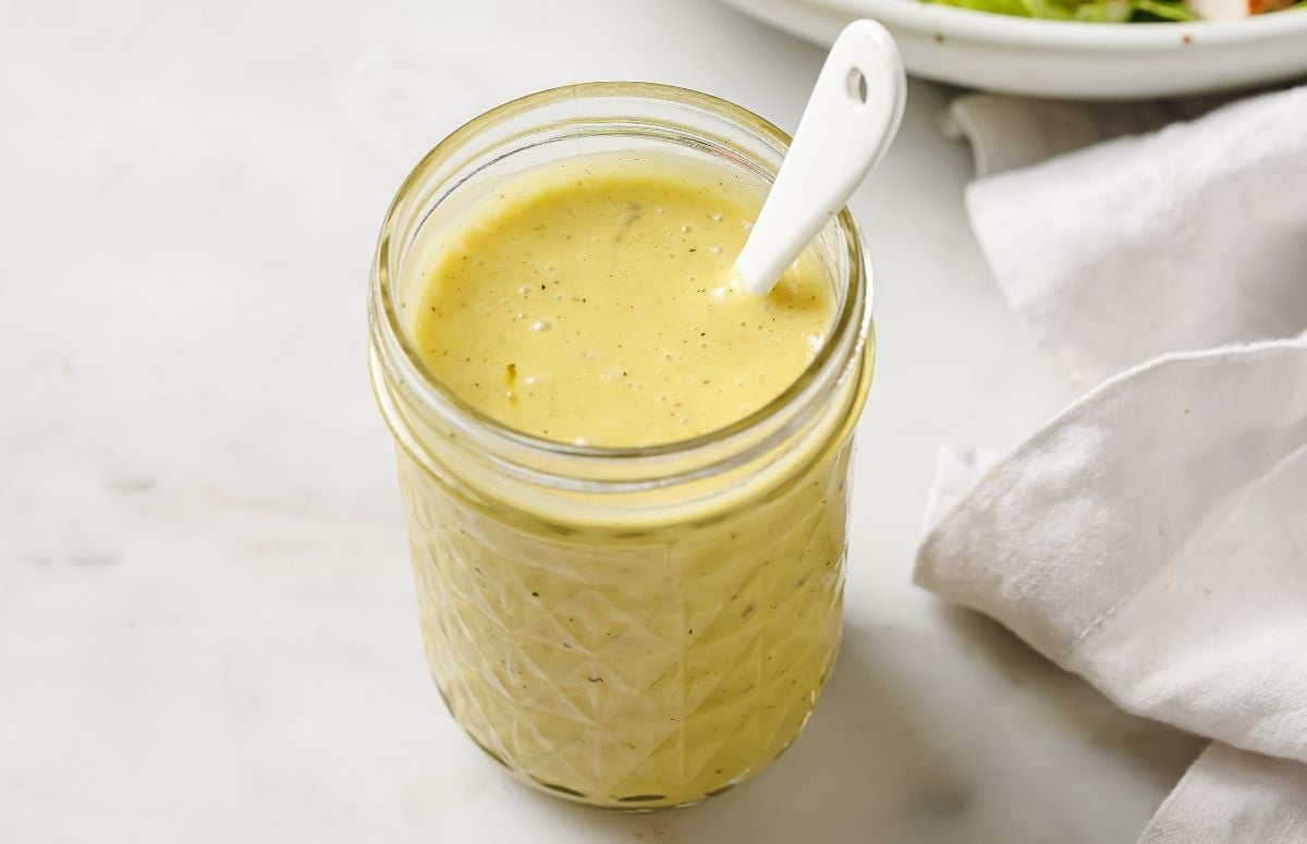 white wine vinaigrette in a glass jar with a spoon