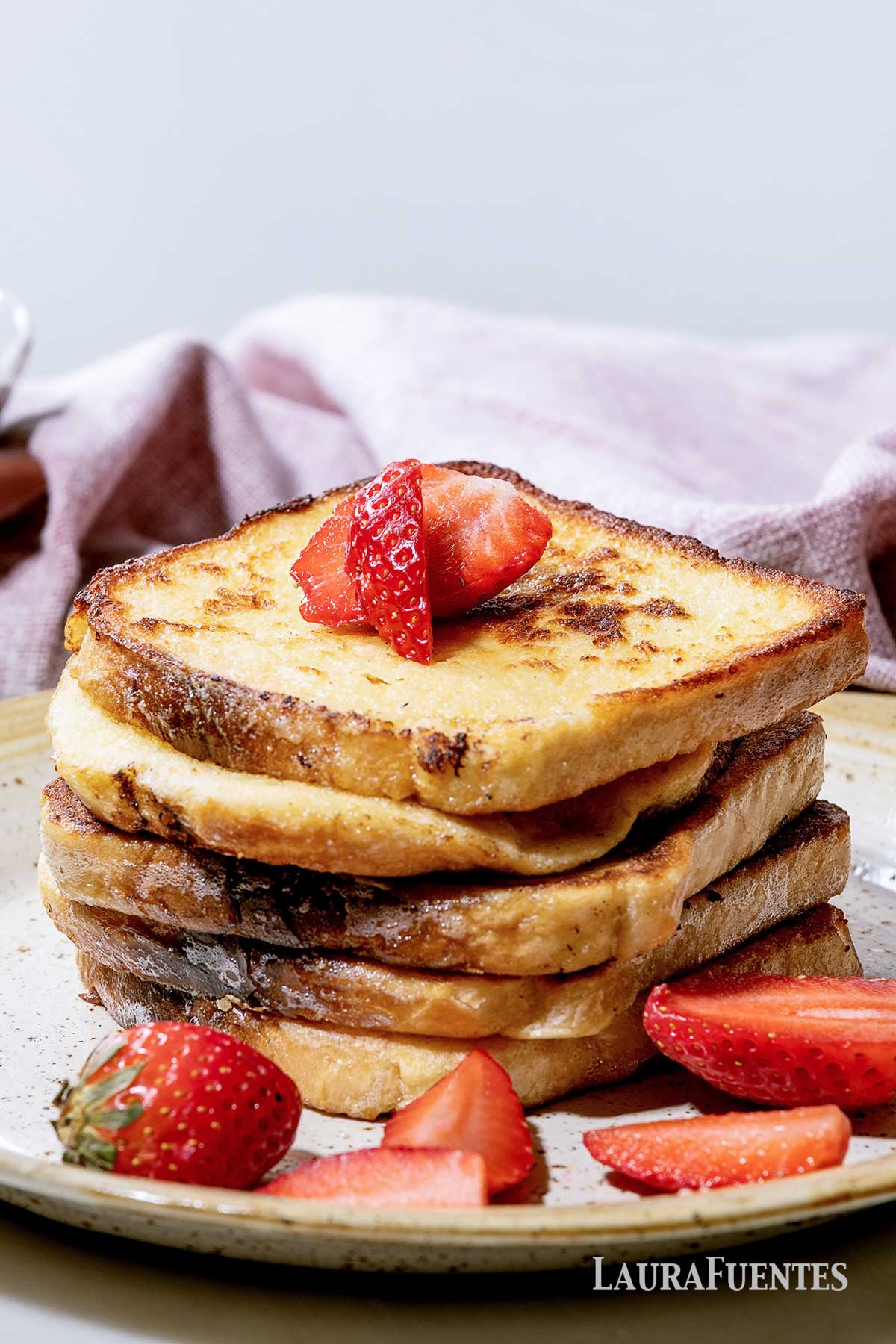 tall stack of French toast topped with strawberries