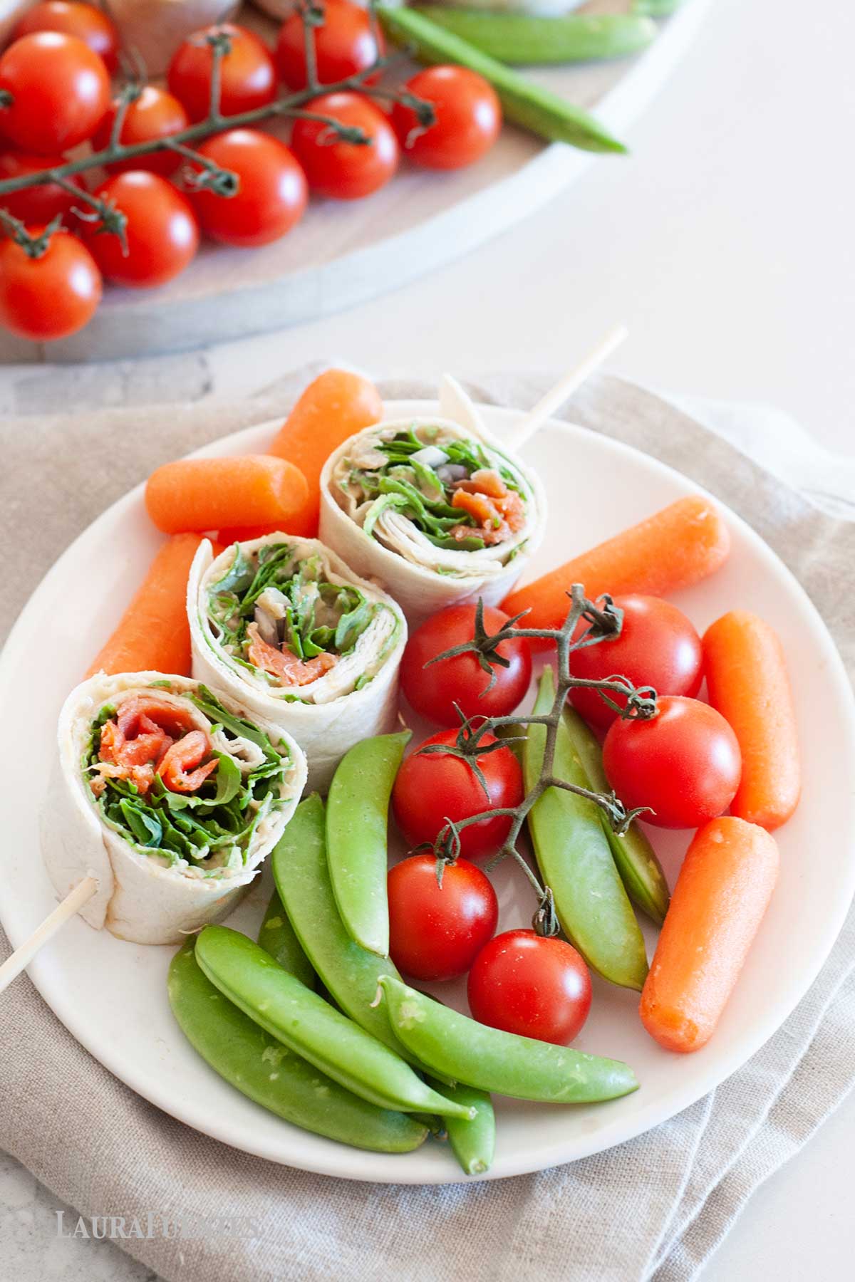 smoked salmon pinwheels with baby carrots, cherry tomatoes and snap peas