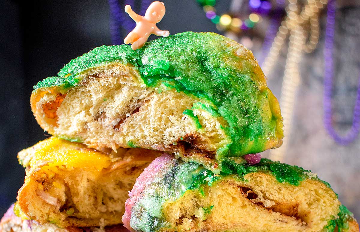 closeup of king cake slices topped with plastic baby