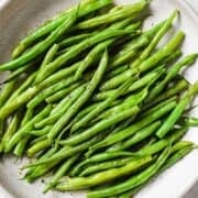 overhead view of steamed green beans in a white dish