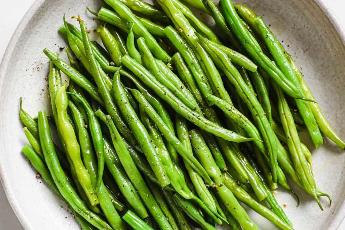 overhead view of steamed green beans in a white dish