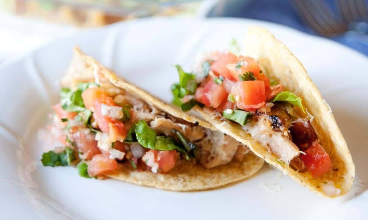 two rotisserie chicken tacos in a white dish