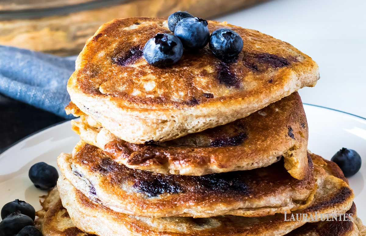 closeup of stack of blueberry pancakes topped with three blueberries