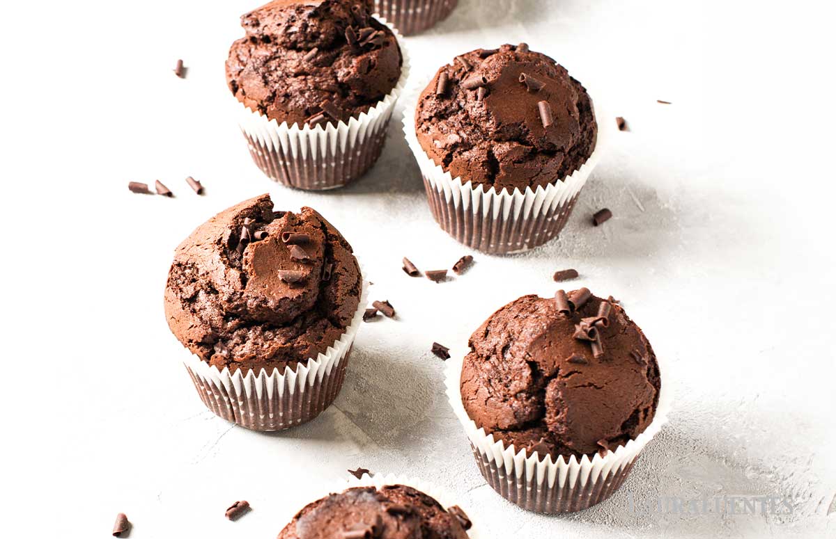 chocolate zucchini muffins on a countertop with shaved chocolate