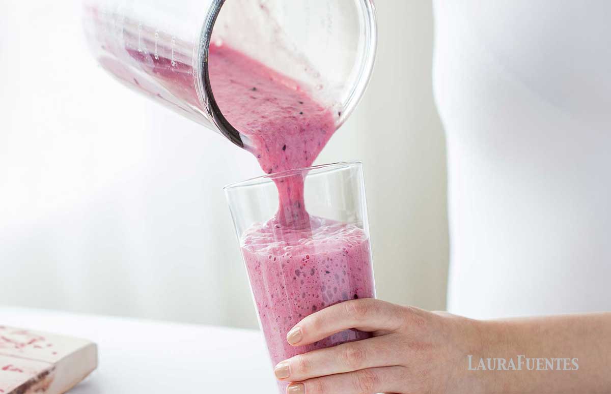pouring a thick pink smoothie into a glass