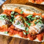 closeup of three large meatballs on a sub topped with cheese
