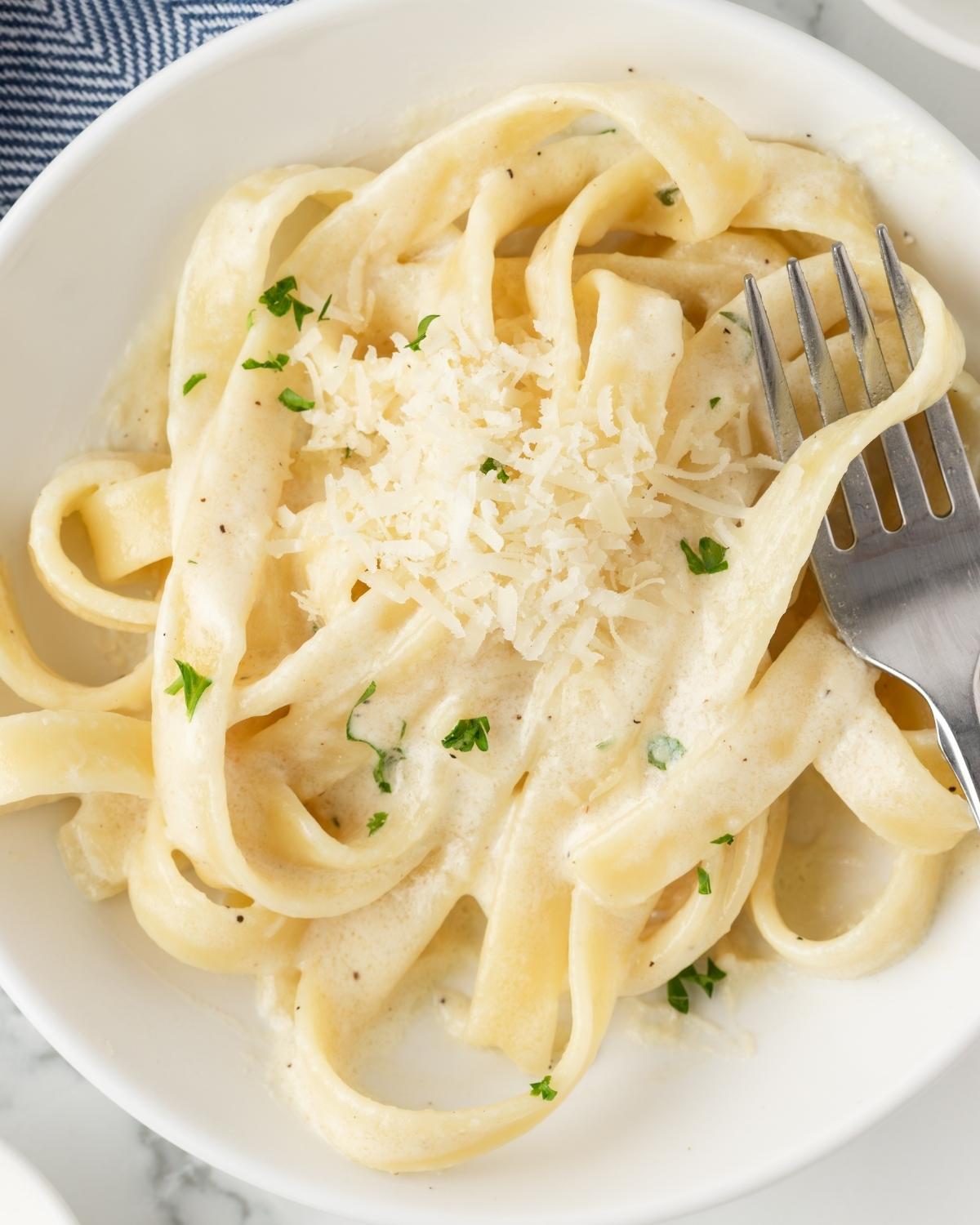 overhead view of a bowl with fettuccine pasta mixed homemade alfredo sauce