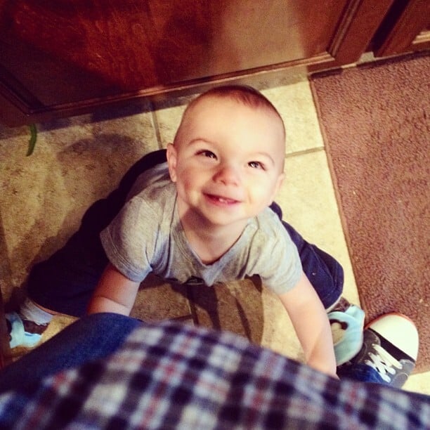 baby G at Laura Fuentes' feet in the kitchen while she tries to cook