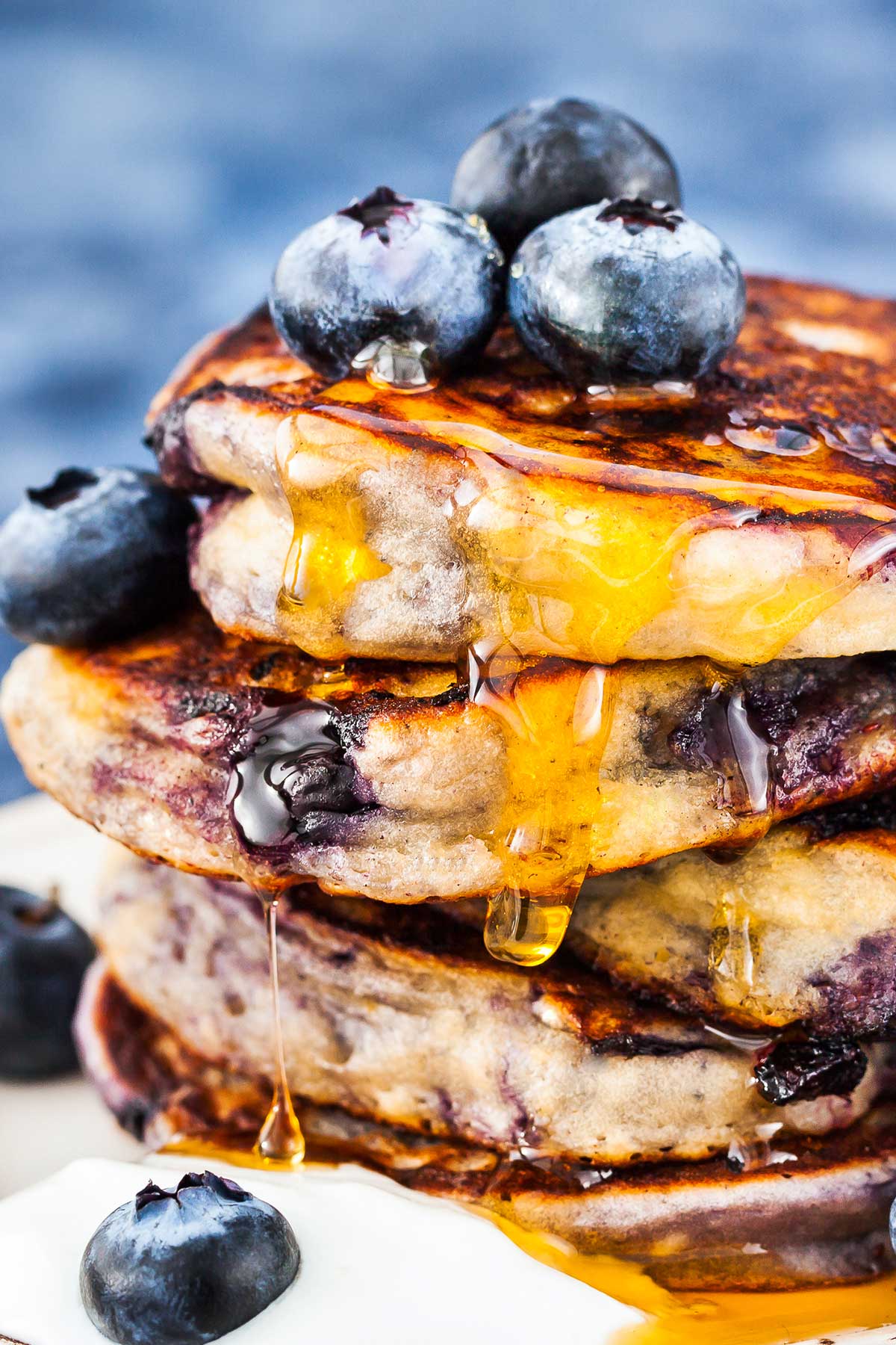 stack of blueberry pancakes on a plate with syrup and blueberries on top