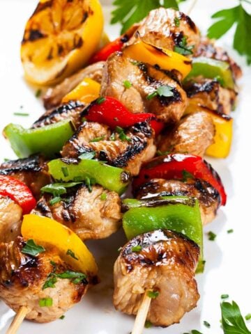 three chicken and vegetable kabobs on a plate