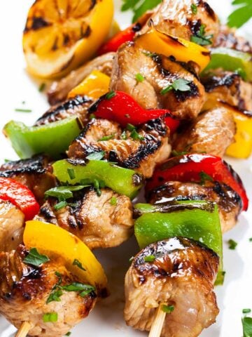 three chicken and vegetable kabobs on a plate