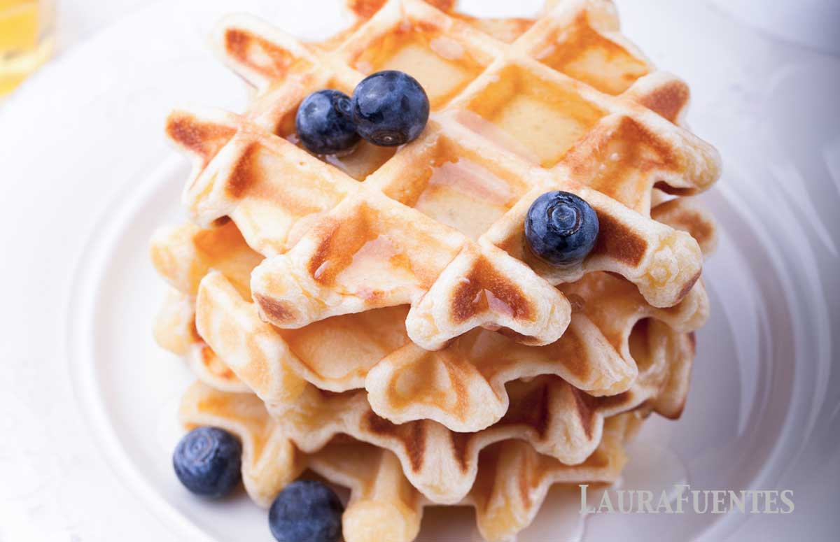 stack of four waffles on a plate with blueberries