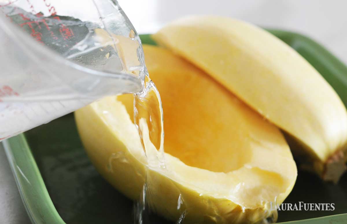 pouring water into a dish with cut spaghetti squash