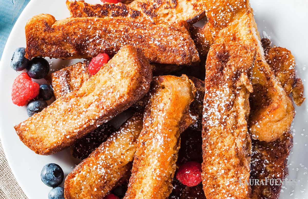Pile of French toast sticks on a plate with berries