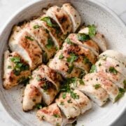 three cooked and sliced chicken breasts in a shallow bowl