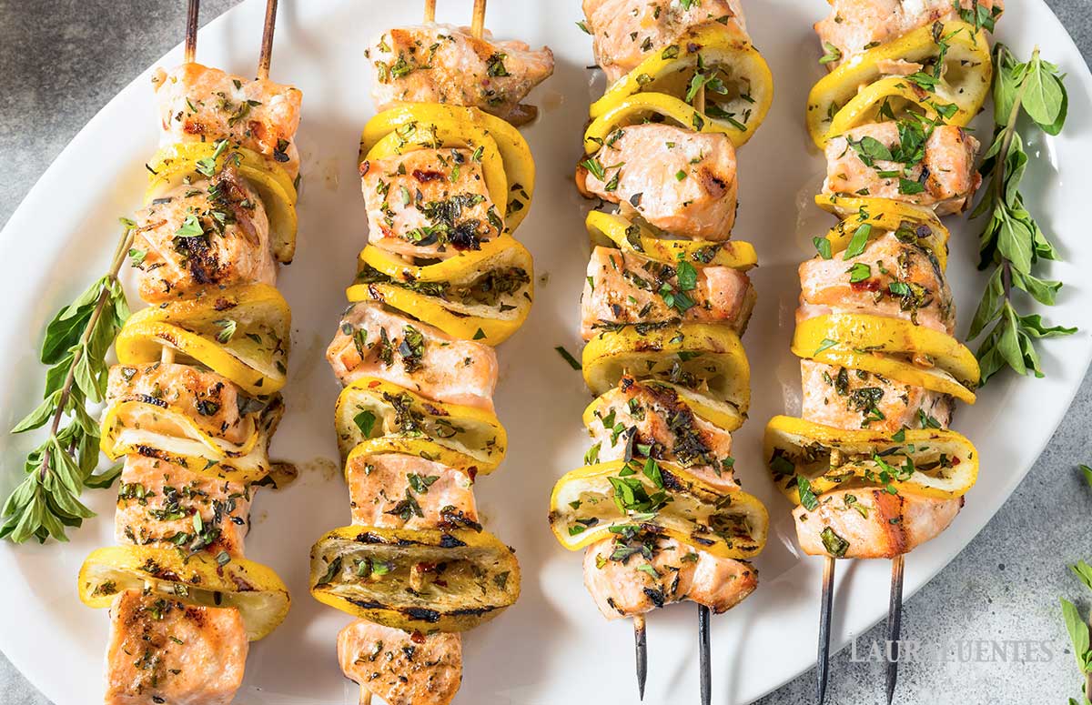 four grilled lemon salmon kabobs on a plate