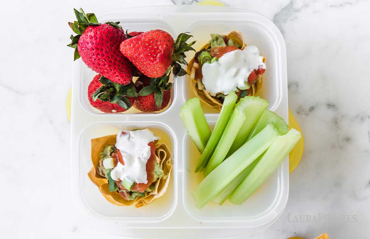 bento box with taco cups, celery, and strawberries.