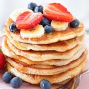 large stack of pancakes topped with fruit