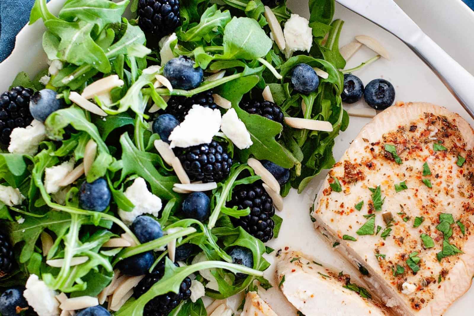 arugula blueberry salad with a chicken breast on a plate