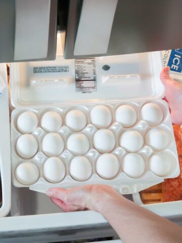 a large carton of eggs being put in a freezer
