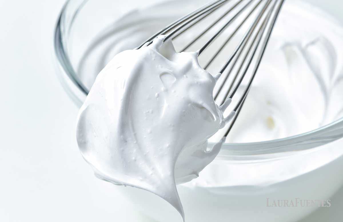 glass bowl of homemade marshmallow fluff with a whisk sitting on top of the bowl