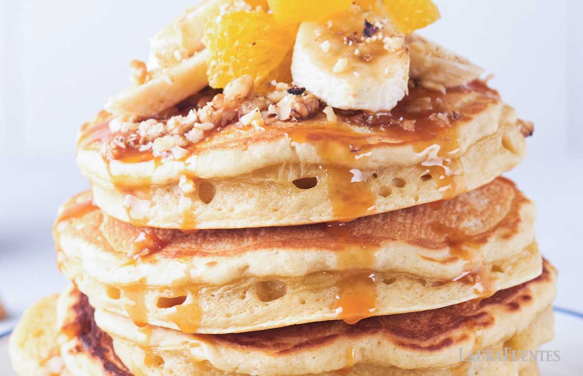 closeup of a stack of pancakes topped with fruit and nuts
