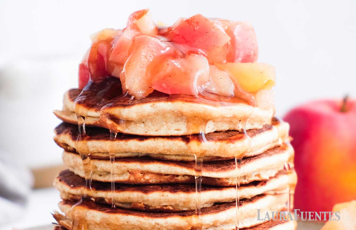 stack of pancakes topped with syrup and cooked apples