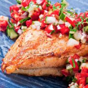 pan seared chicken breast on a blue plate topped with margarita salsa