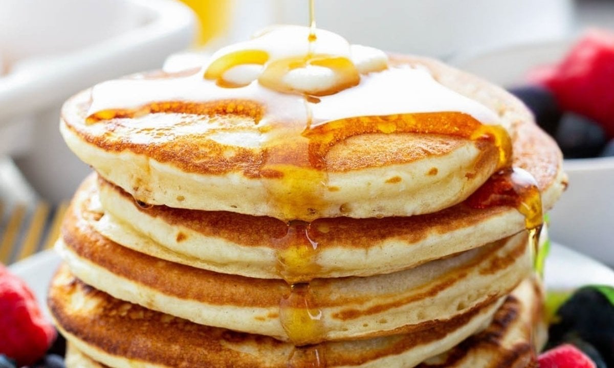 close up of fluffy yeast pancakes topped with butter and syrup
