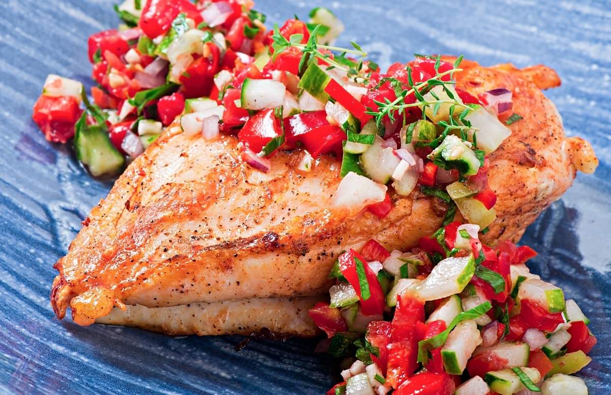 cooked chicken breast on a blue plate topped with margarita salsa