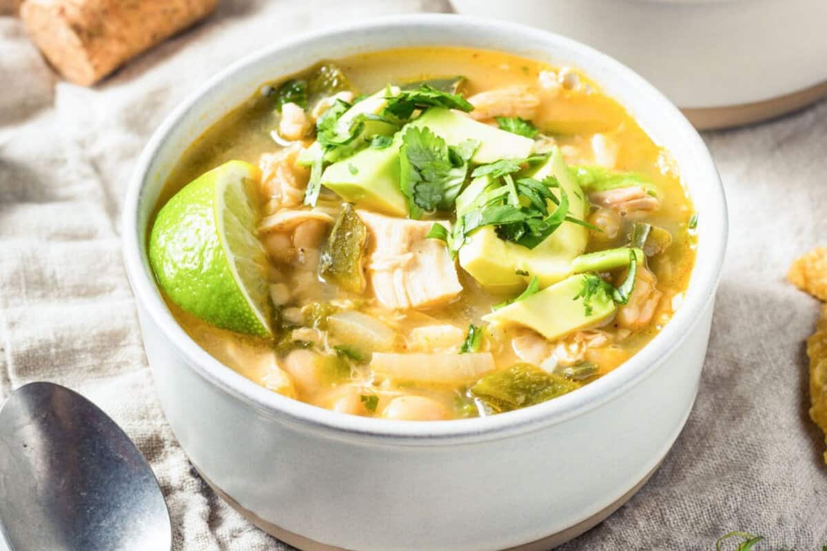 a bowl of rotisserie chicken chili topped with lime and avocado