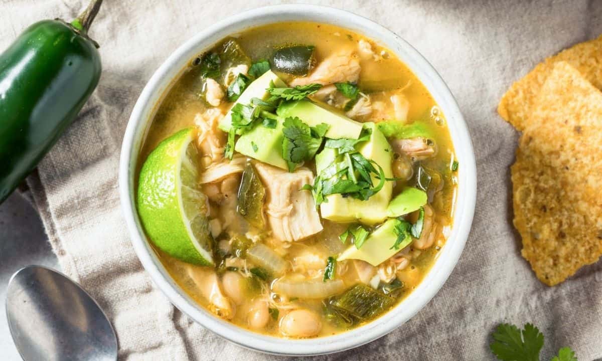 a bowl of rotisserie chicken chili topped with lime and avocado